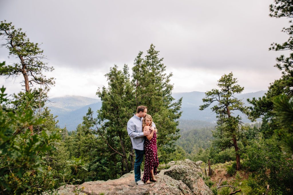Morrison engagement session at Mount Falcon Park, couple standing on a rock embracing each other